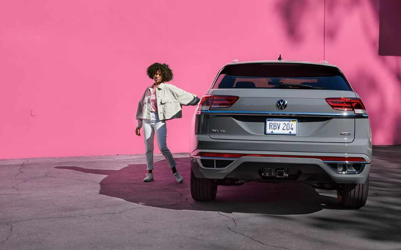 rear view of a 2023 VW Atlas next to its driver in front of a pink wall
