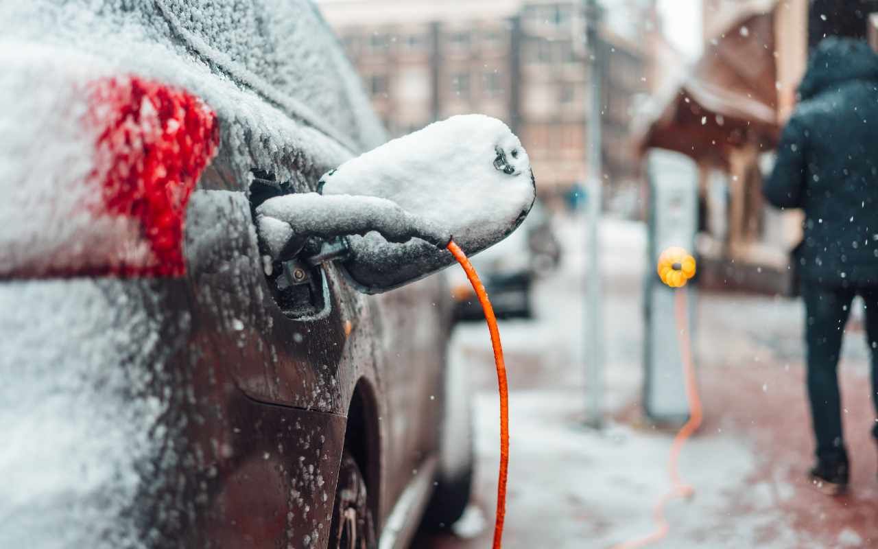 zoomed in view of a snow-covered vehicle plugged in a charging station