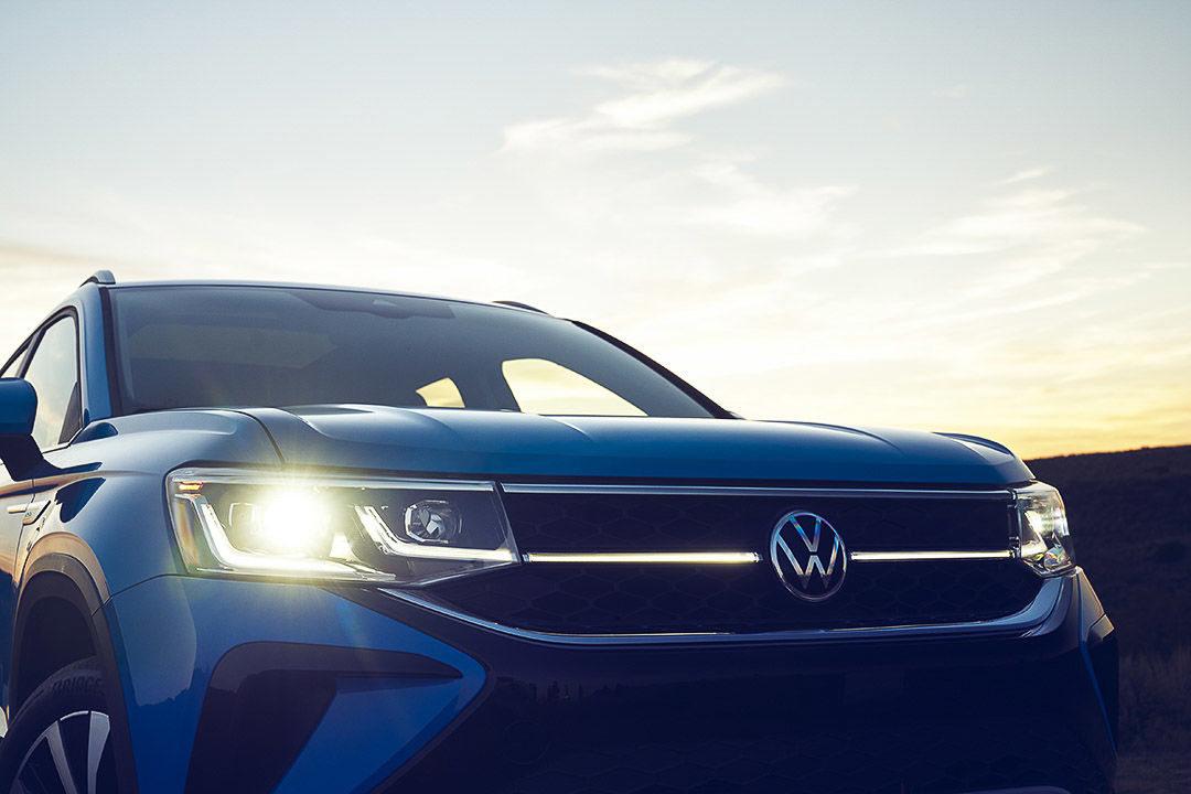 close up front view of the 2022 Volkswagen Taos with the headlights on