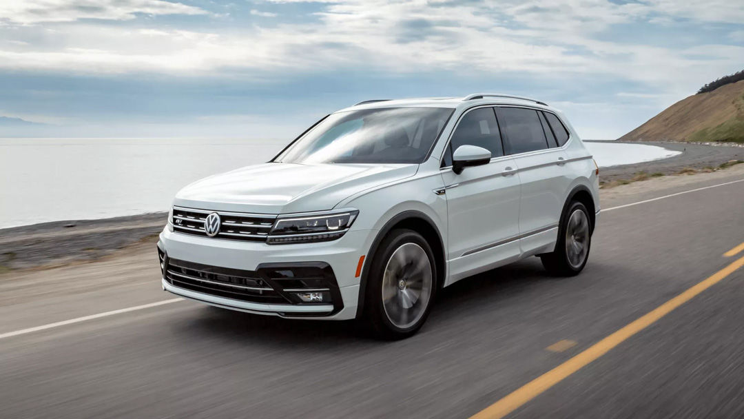 three quarter front view of the 2021 Volkswagen Tiguan driven on a road close to a large body of water