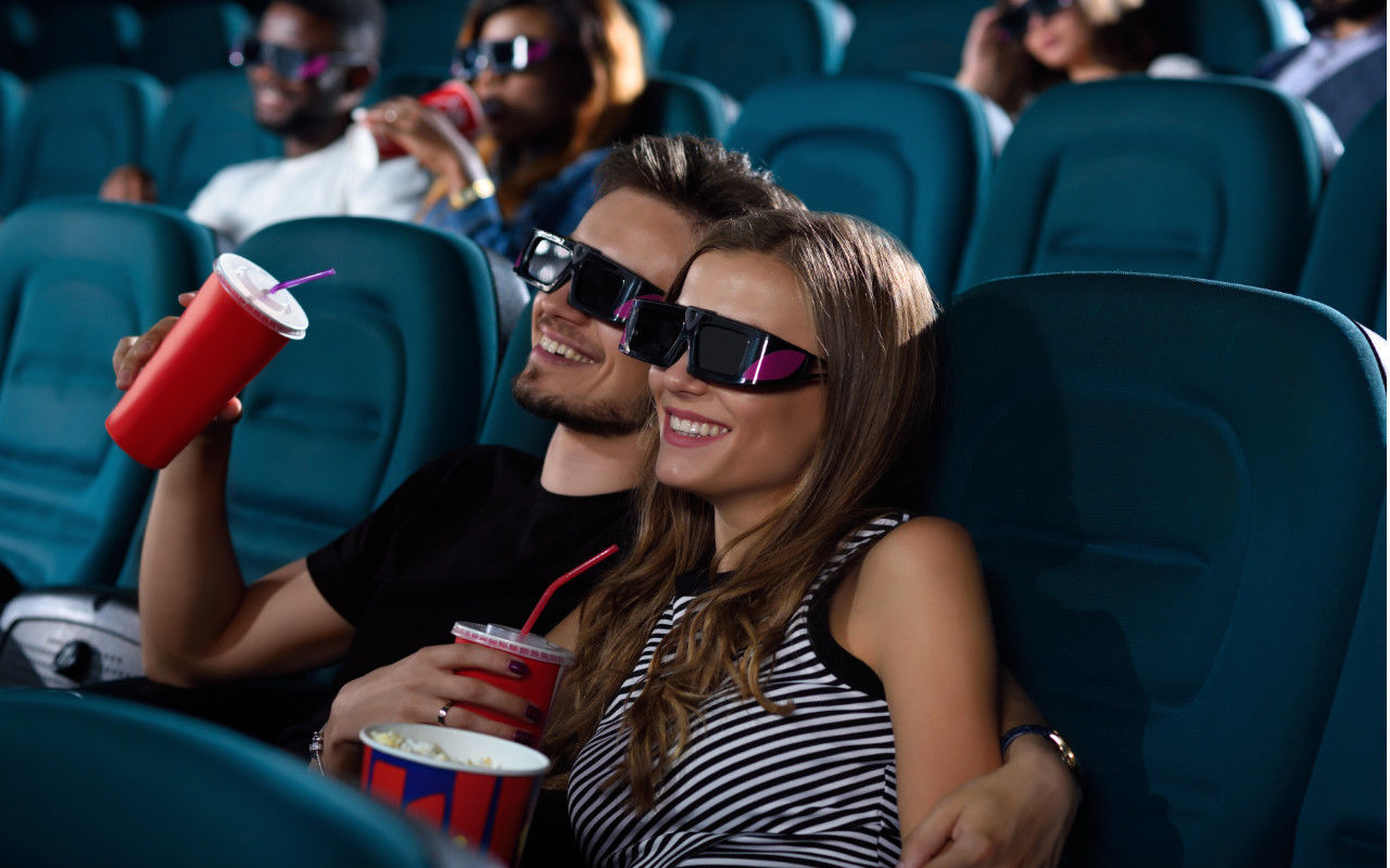 couple at the movies with 3d glasses on and some popcorn and drinks