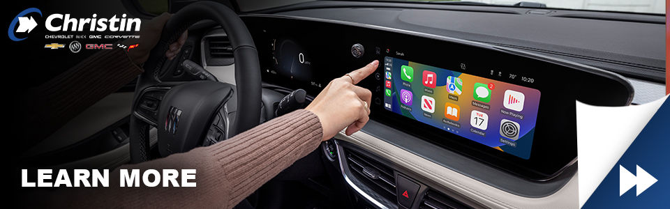 Image of a person behind the wheel playing with the touchscreen of their 2024 Buick Encore GX for sale at Christin Chevrolet Buick GMC