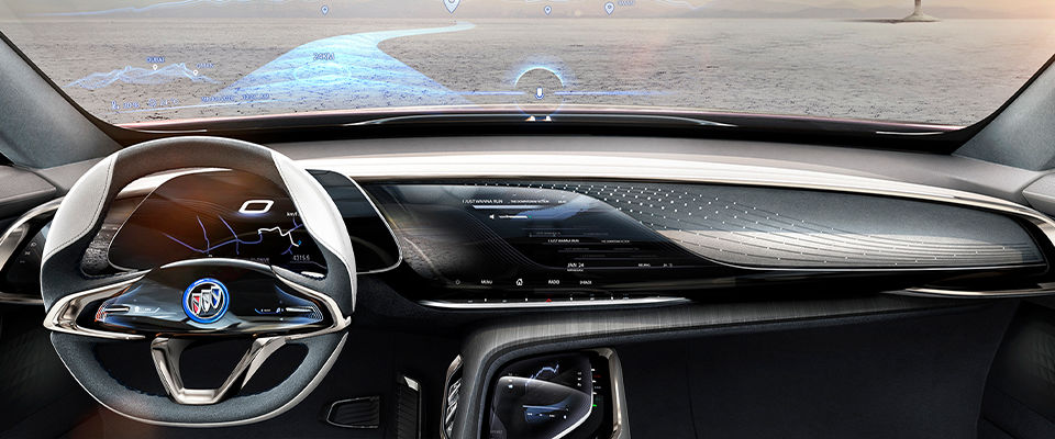 Image that shows the interior of the Buick Enspire car as well as a steering wheel halfway between a rectangle and an oval shape. A long dashboard and a marked absence of physical buttons