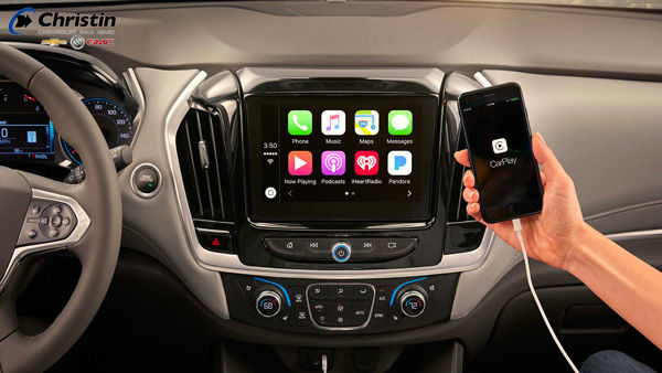 Image d'une main près de l'écran numérique du tableau de bord qui indique la compatibilité du téléphone avec la voiture via l'application CarPlay.