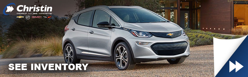 gray 2021 chevrolet bolt ev electric vehicle on a road near montreal with chrstin automobiles logo