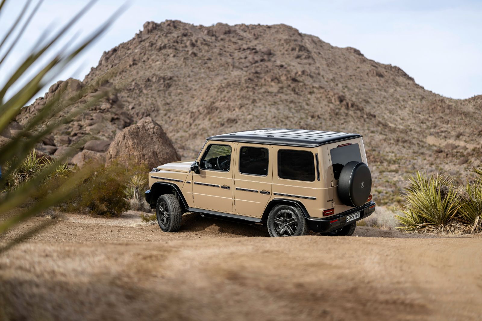2026 Mercedes-Benz G-Class - Rear three-quarter view of a tan 2026 Mercedes-Benz G-Class in a desert setting - Mercedes-Benz Brampton - New car dealership in Brampton, Ontario
