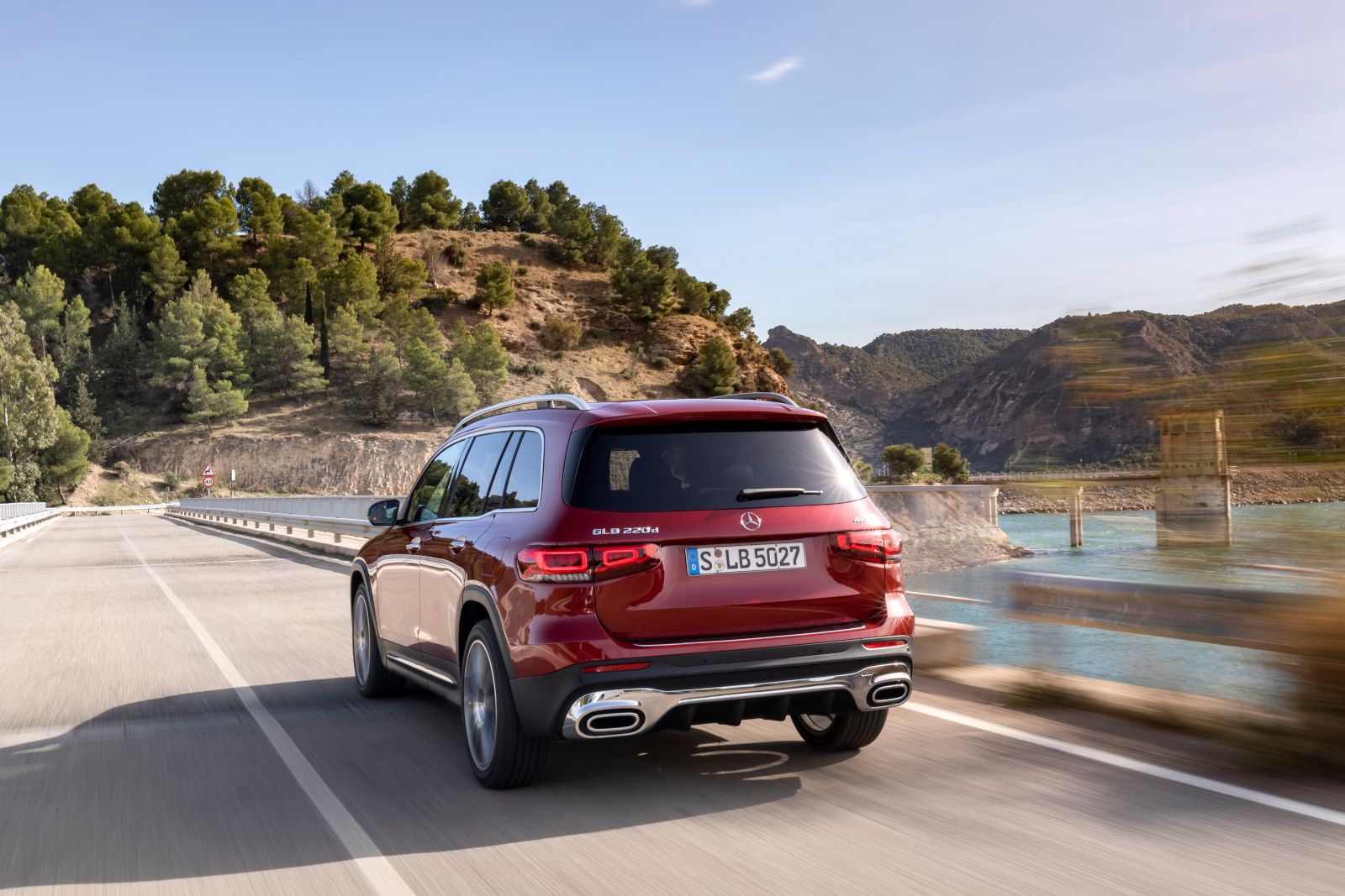 2026 Mercedes-Benz GLB 250 - Rear three-quarter view of a red 2026 Mercedes-Benz GLB 250 driving on a bridge - Mercedes-Benz Brampton - New car dealership in Brampton, Ontario