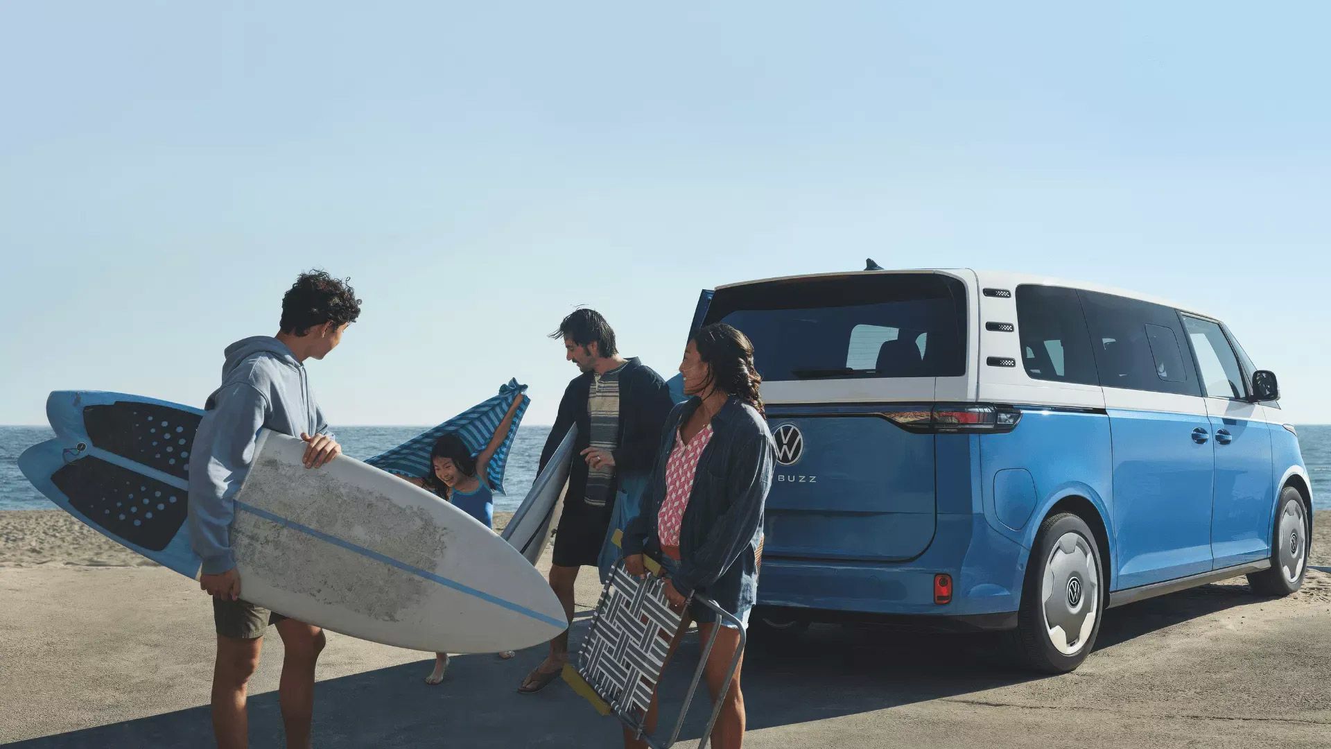 ID. Buzz à la plage avec famille portant des surfs