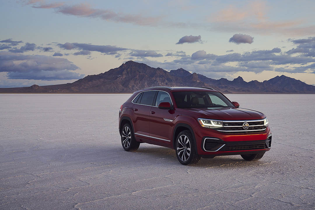 The 2021 VW Atlas Cross Sport in aurora red chrome parked on deserted land with its back to the rockies