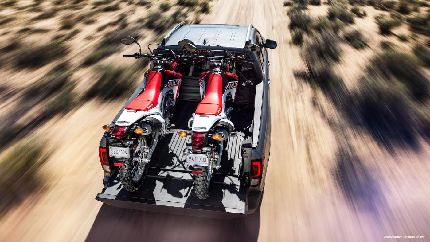 Vue de dessus du Honda Ridgeline Touring 2021 remorquant deux motocross sur la route d'un désert
