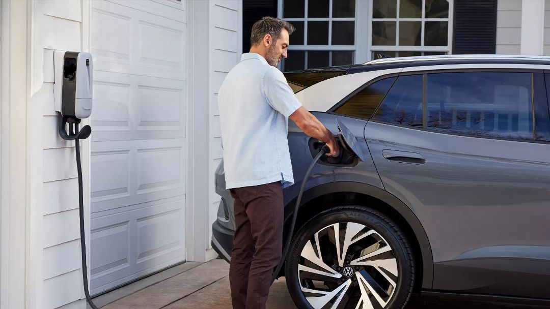 A man plugs his 2025 Volkswagen ID.4 Pro into a charging station