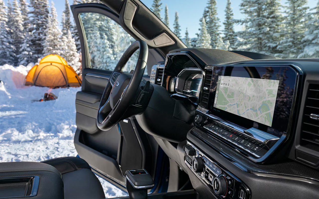 Vue de l'intérieur du Chevrolet Silverado 1500 portirère ouverte sur sentier de neige, avec camping hivernal