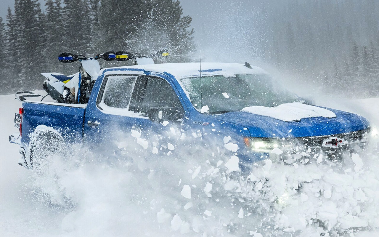 Vue latérale du Chevrolet Silverado 1500 en pleine puissance traversant un sentier de neige