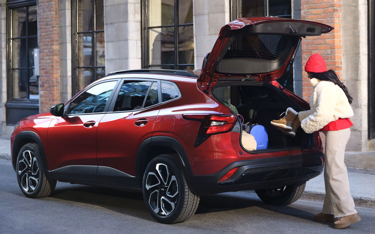 Vue arrière du Chevrolet Trax 2024 avec une jeune damme ajoutant des matériels dans la valise