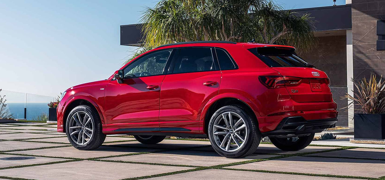 Vue arrière de l'Audi Q3 2024 stationné devant un batîment avec vue sur mer