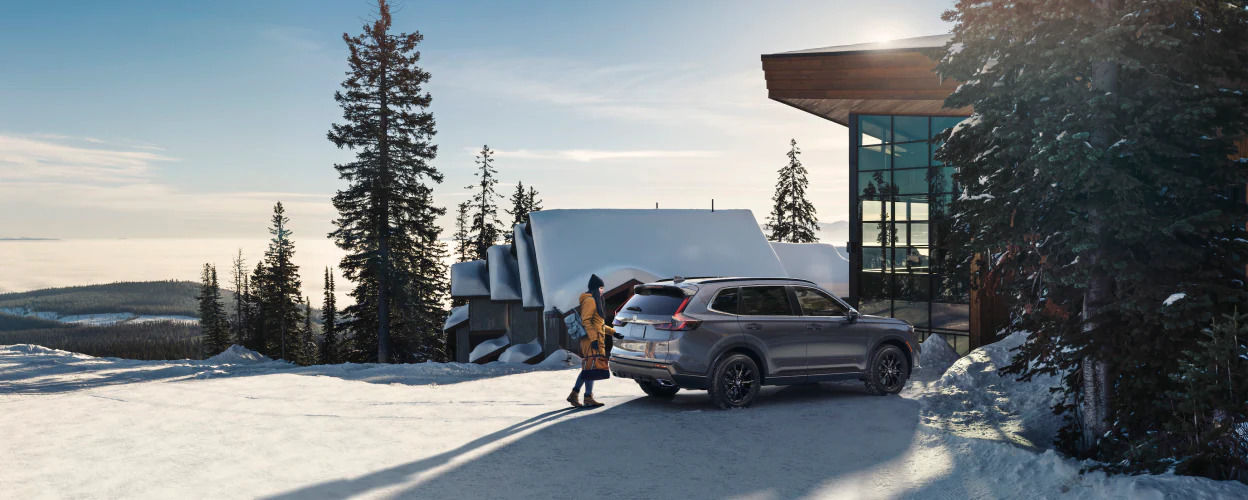 rear side view of a 2023 Honda CR-V in front of a house on a snowy mountain