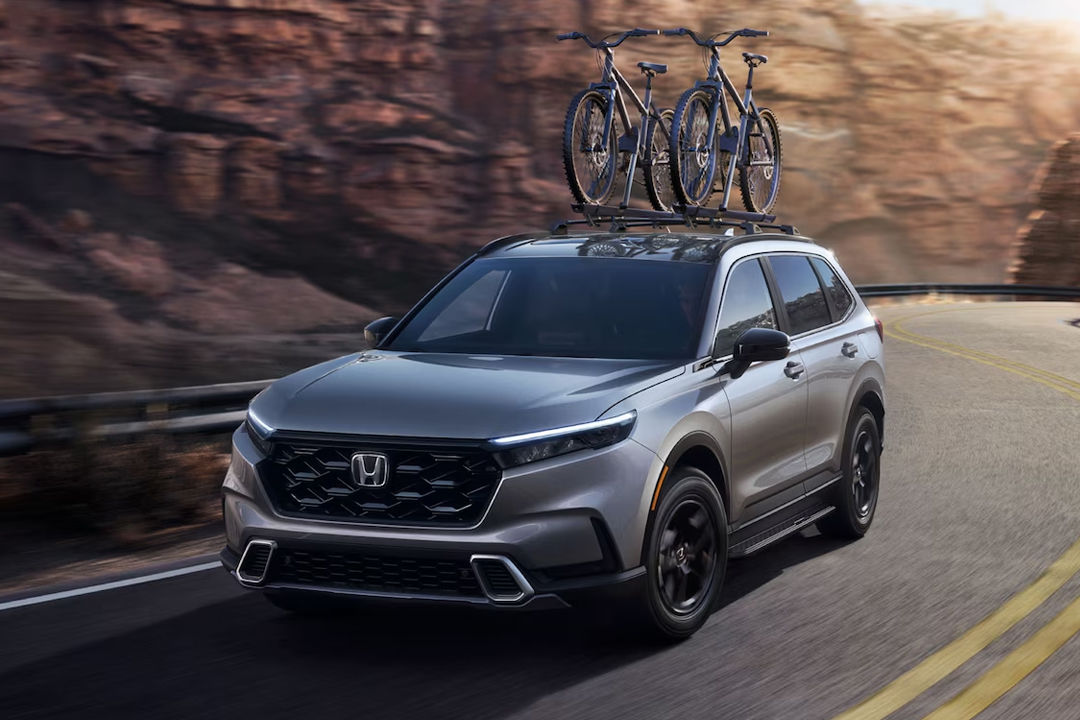 Vue avant et latérale du Honda CR-V  hybride 2024 sur route avec support à vélo