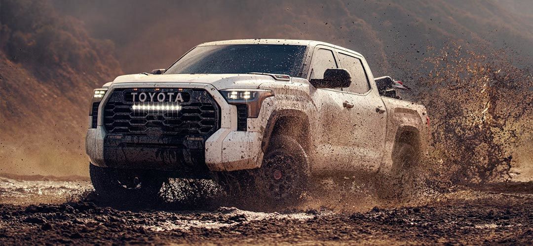 Vue 3/4 avant et latérale du Toyota Tundra 2024 traversant une marre de boue