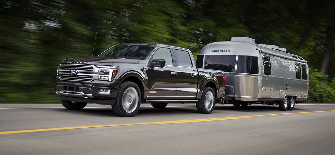 Vue 3/4 avant et latérale du F-150 2024 sur route en pleine puissance avec roulotte