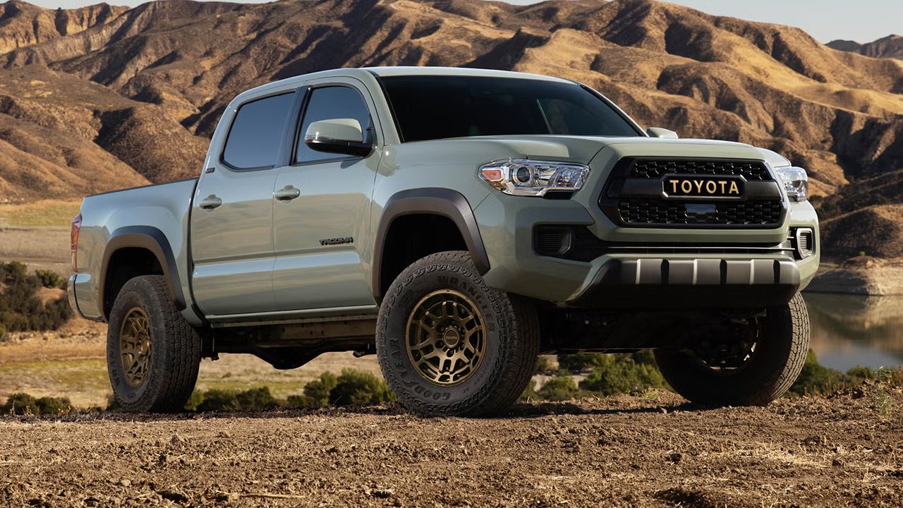 Vue 3/4 avant et lat&eacute;rale du Toyota Tacoma 2022 sur chemin de terre avec vue de montagne
