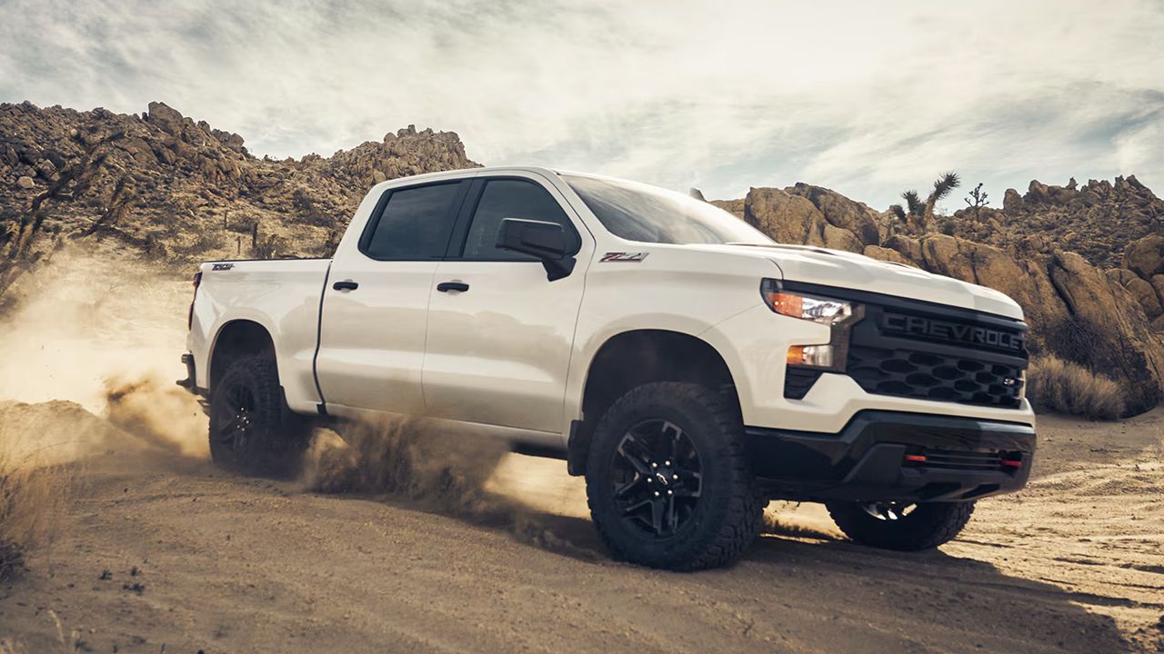 Vue 3/4 avant et lat&eacute;rale du Silverado&nbsp;1500 2026 en pleine puissance sur un chemin de sable