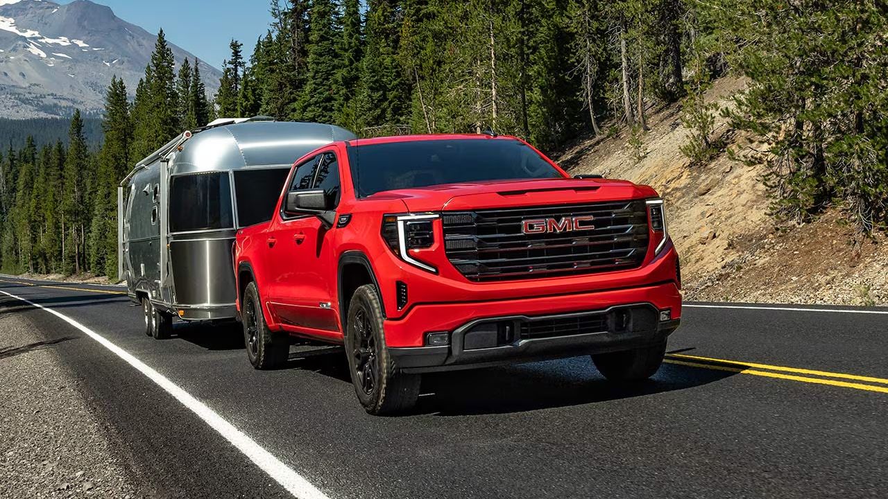 3/4 front and side view of the GMC Sierra 1500 on the road pulling a trailer