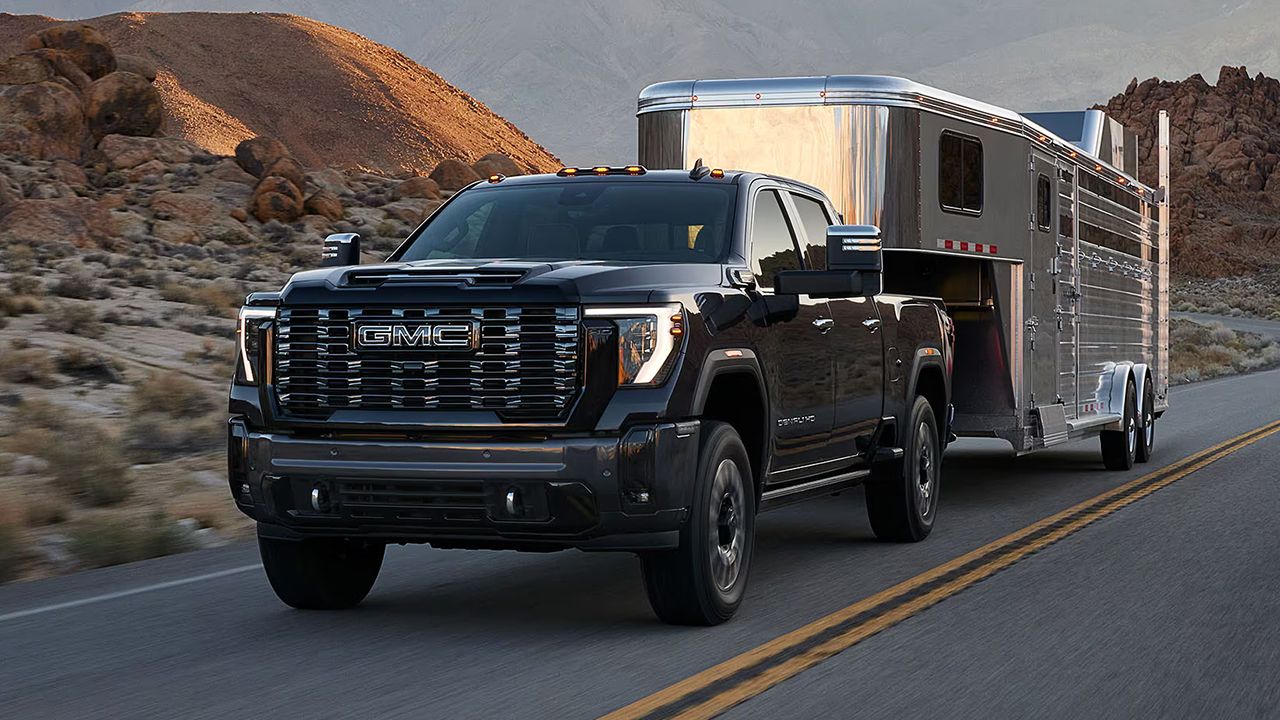 3/4 front and side view of the GMC Sierra 2500 on the road pulling a trailer