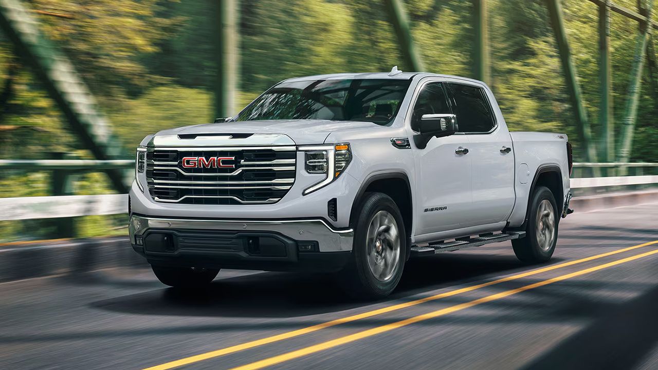 Vue avant et lat&eacute;rale du GMC Sierra 1500 2026 sur route traversant un pont en pleine puissance