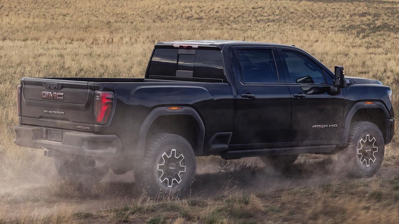 Vue arri&egrave;re du GMC Sierra&nbsp;2500 2026 sur chemin de terre en pleine puissance