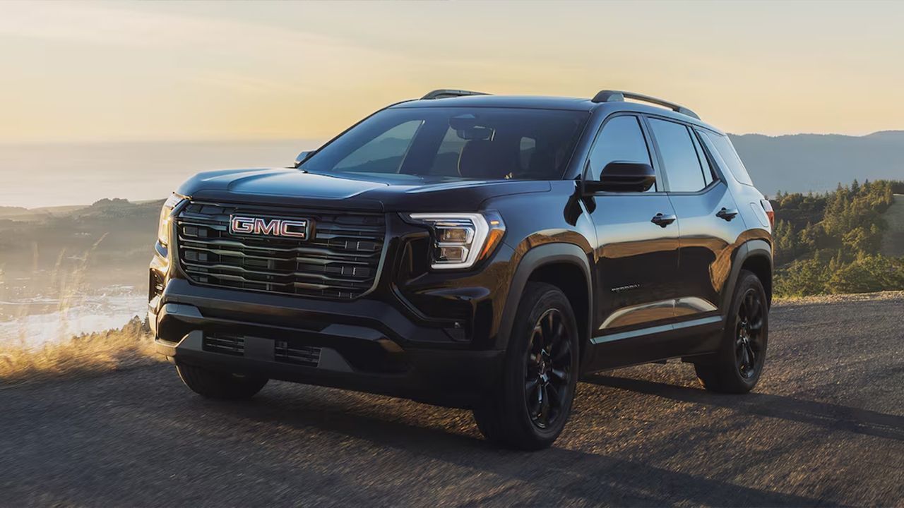 Vue 3/4 avant et lat&eacute;rale du GMC Terrain 2026 sur route en pleine puissance avec coucher de soleil