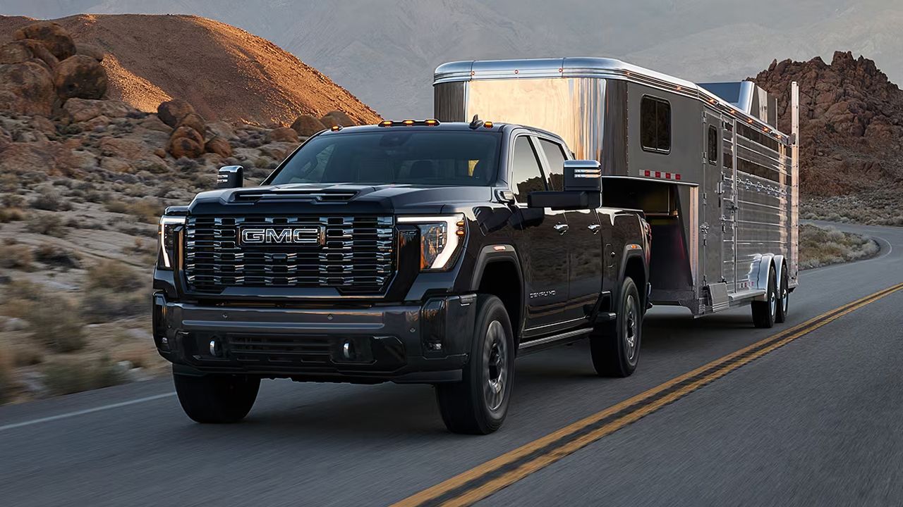 Vue 3/4 avant et lat&eacute;rale du GMC Sierra&nbsp;2500 2026 sur route tiran une remorque &agrave; chevaux