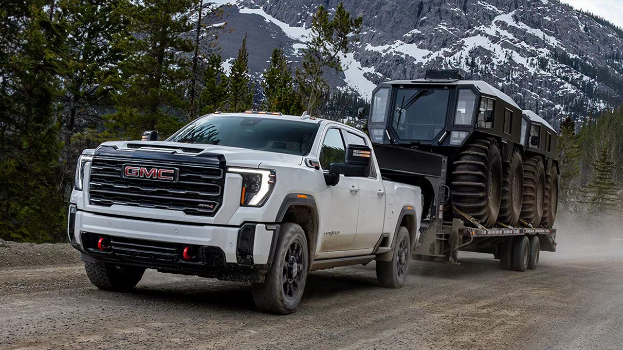 Vue 3/4 avant et lat&eacute;rale du GMC Sierra&nbsp;3500 2026 tirant avec puissance une remorque avec machinerie lourde