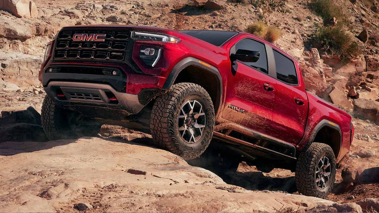 Vue 3/4 avant et lat&eacute;rale du GMC Canyon 2026 montant des rochers en pleine puissance