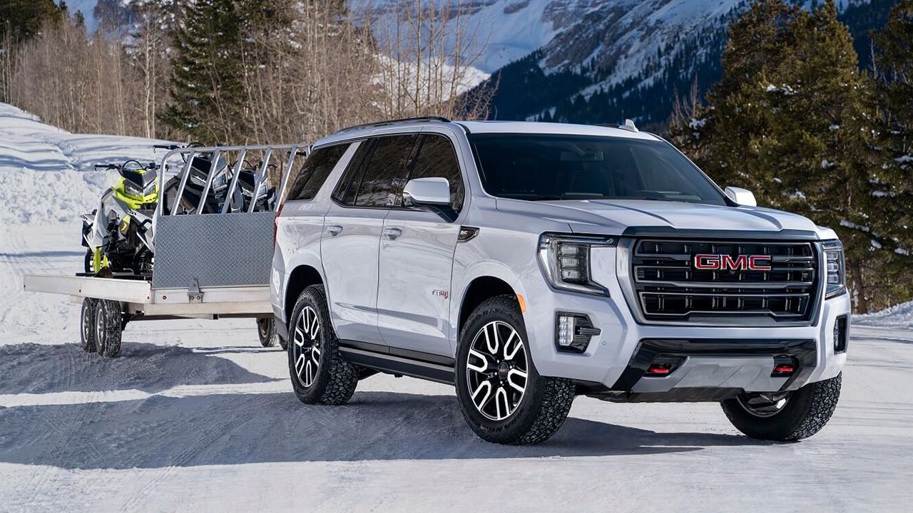 Vue 3/4 avant et lat&eacute;rale du GMC Yukon 2026 sur neige avec remorque &agrave; motoneige