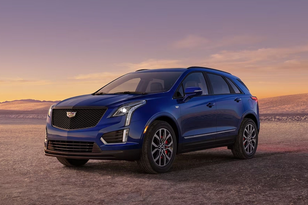 Front and side view of the Cadillac XT5 2024 on a sandy road and sunset