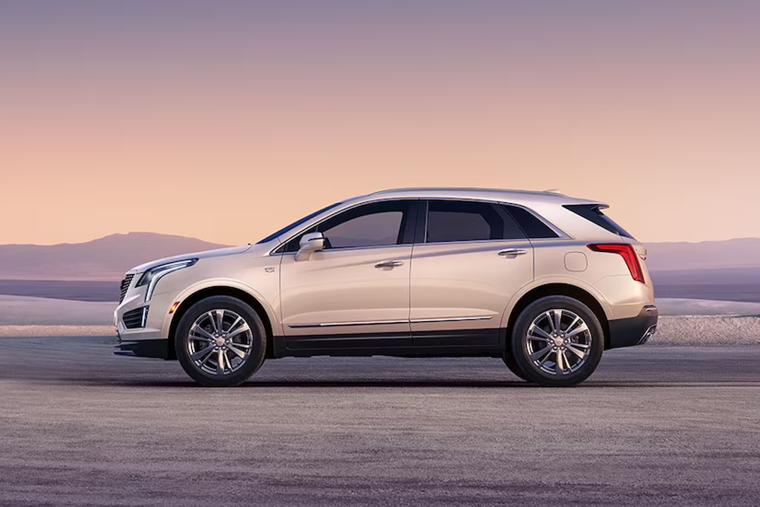 Side view of Cadillac XT5 2024 on sandy road with sunset
