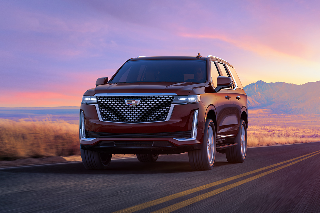 Front view of Cadillac Escalade 2024 on road with sunset
