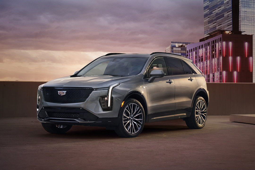 Front view of the Cadillac XT4 2024 in a city parking lot with headlights on