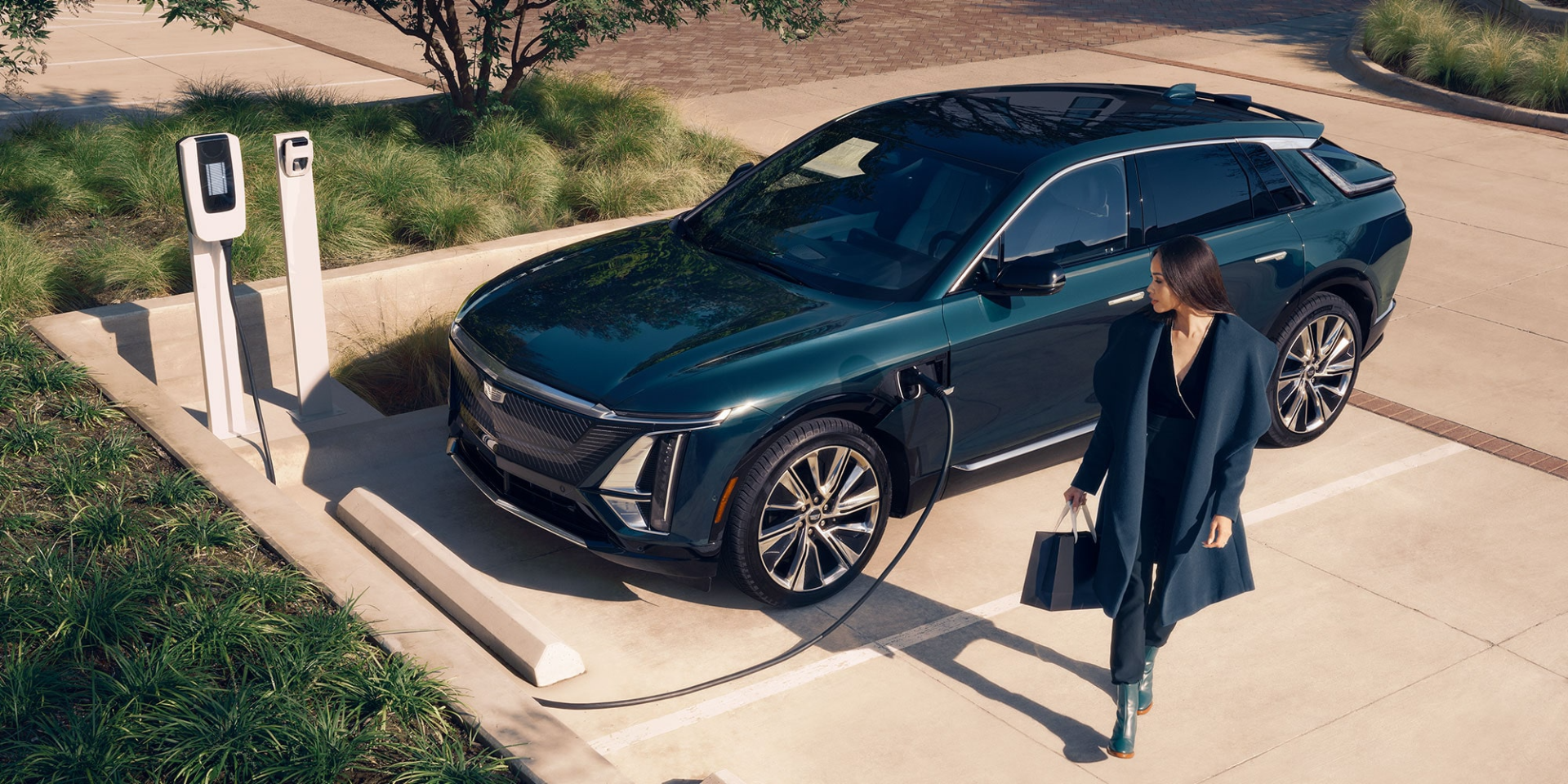 Une femme regarde un Cadillac Lyriq 2025 en train d’être rechargé