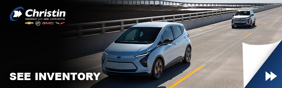 white 2022 chevrolet bolt ev electric car driving on a montreal road with christin automobiles logo
