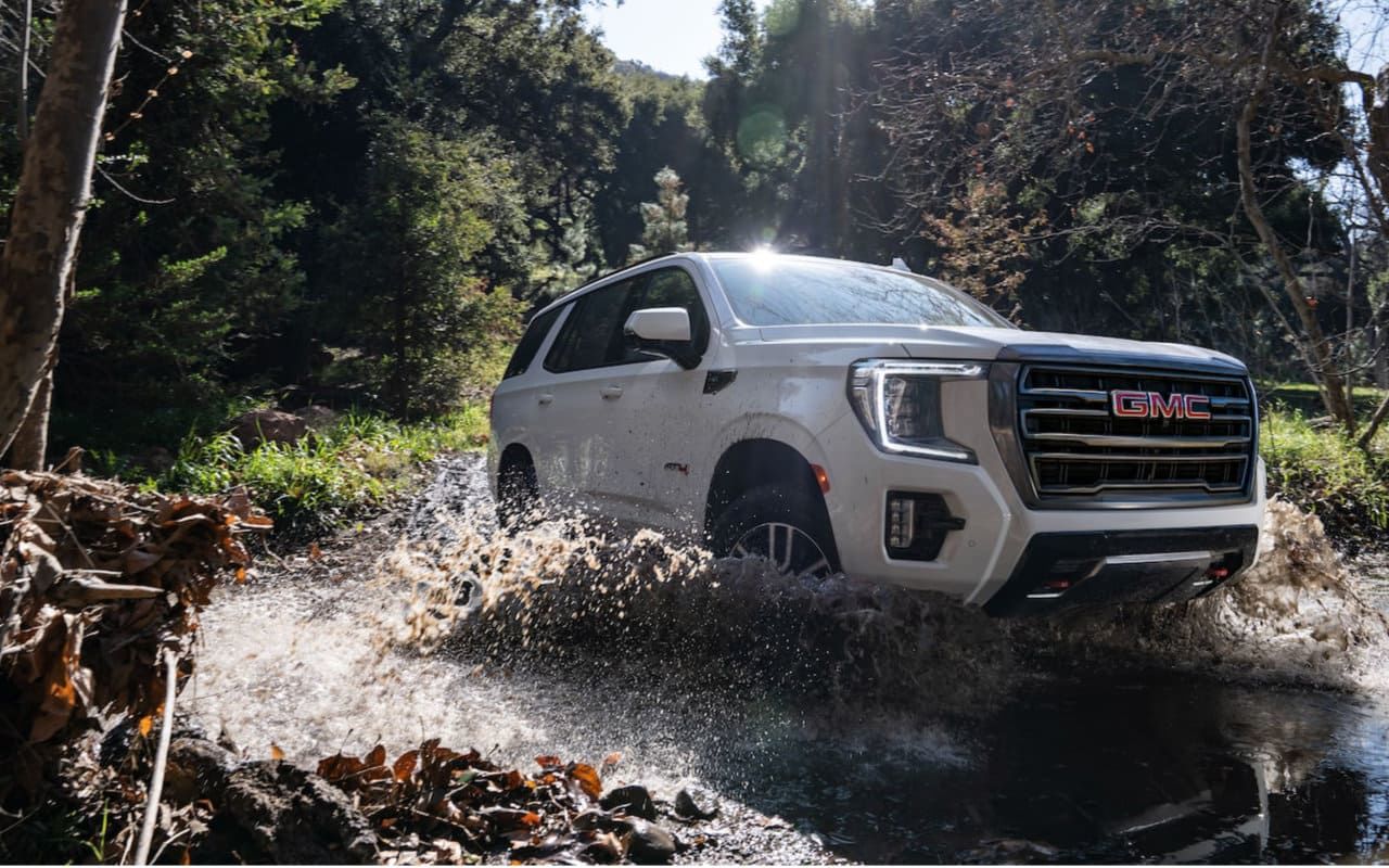 vue d'un GMC Yuko0n 2023 qui taverse un cours d'eau en forêt