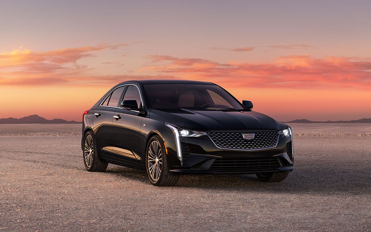 Vue avant du Cadillac CT4 2024 sur route de sable avec coucher de soleil