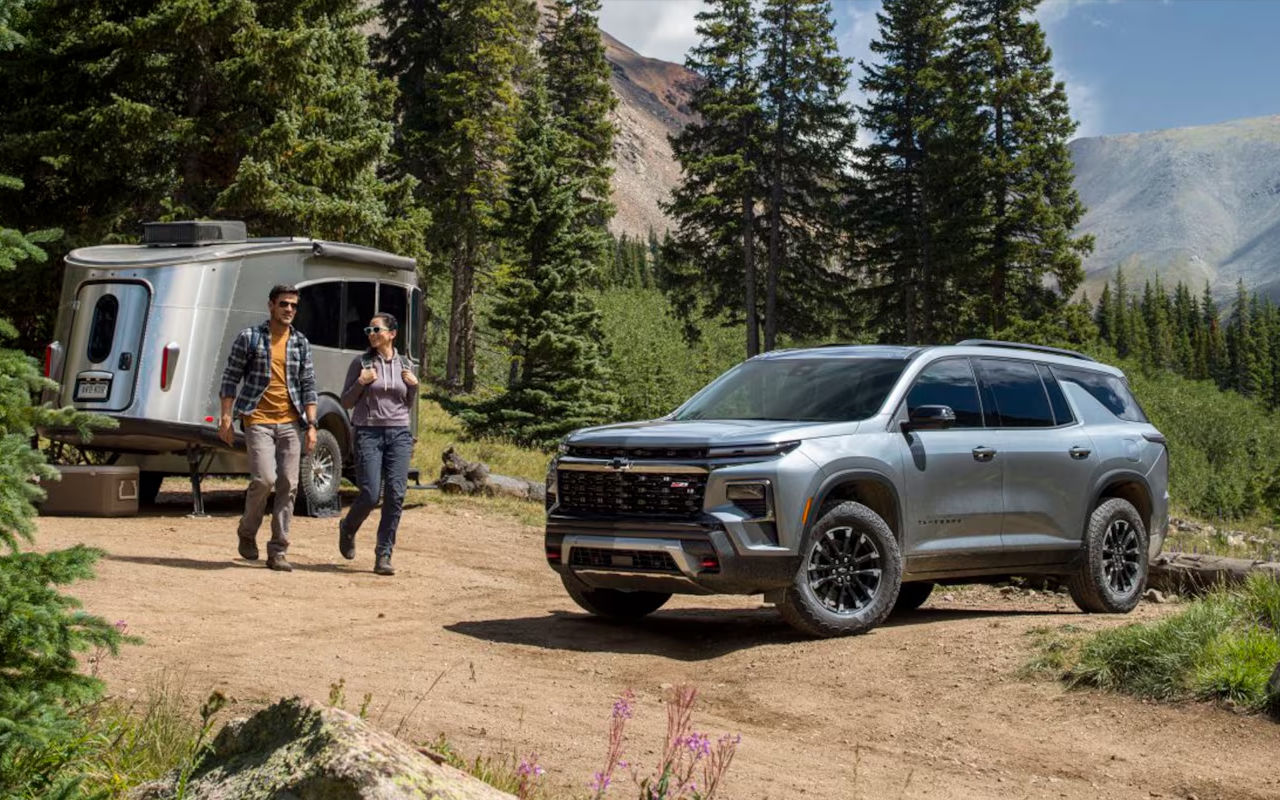 Vue 3/4 avant et latérale du Chevrolet Traverse 2025 en arrêt dans une montagne avec une roulotte garé