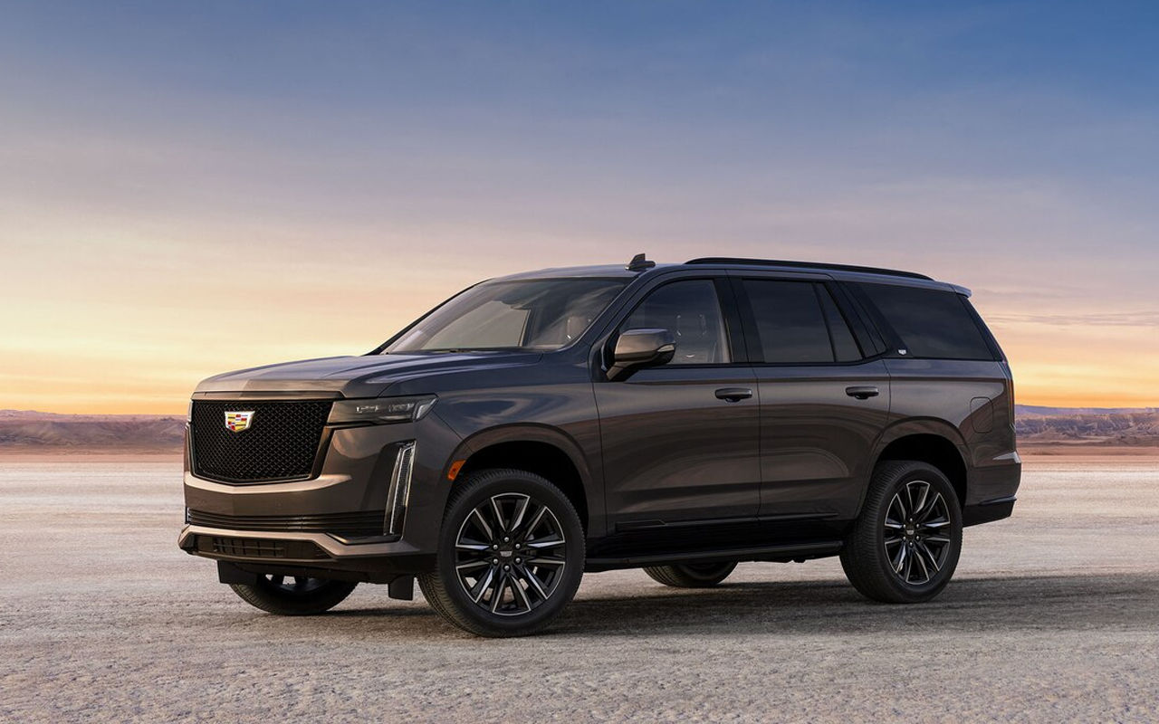 Vue latérale du Cadillac Escalade 2024 sur route de sable avec coucher de soleil