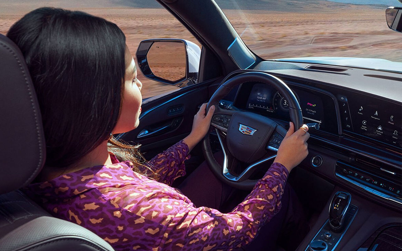 Vue intérieur du Cadillac Escalade 2024 avec femme au volant dans une route de sable