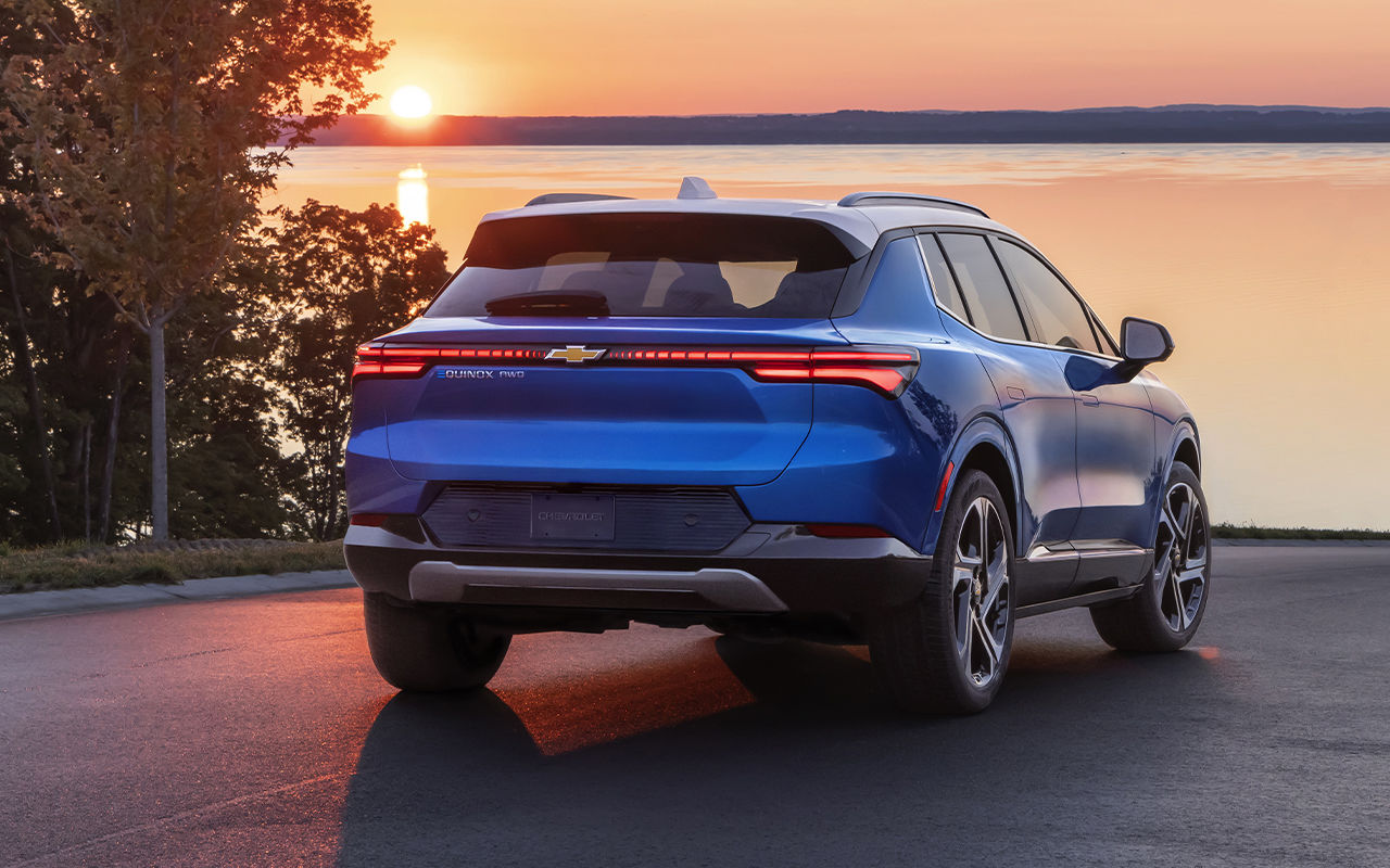 Vue arrière du Chevrolet Equinox EV 2024 en arrêt sur le bord de mer, avec coucher de soleil