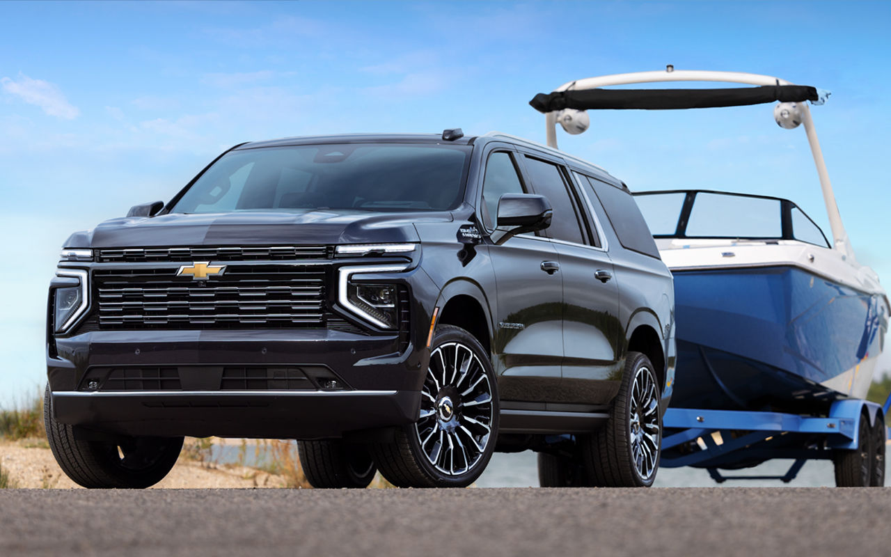 Vue 3/4 avant et latérale du Chevrolet Suburban 2025 avec remorque et bateau