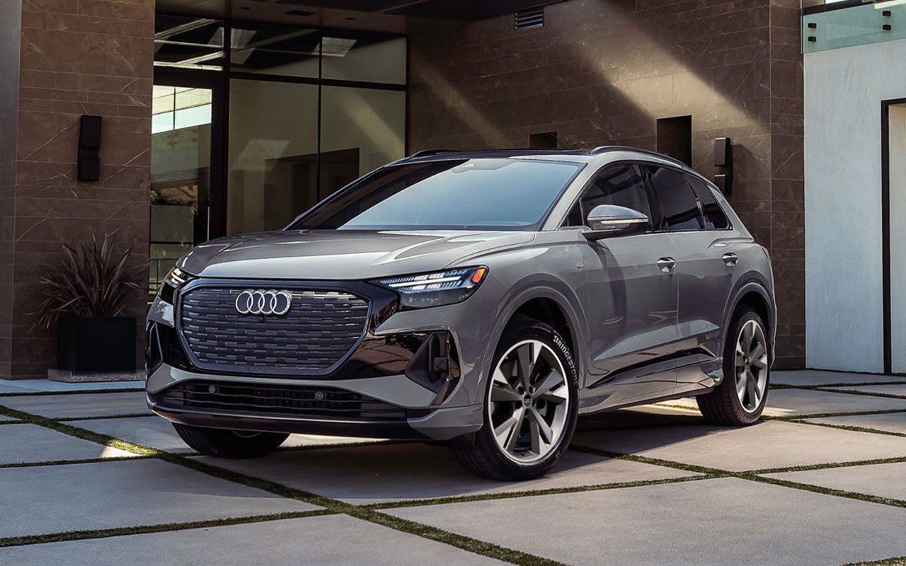 Vue 3/4 avant et latérale de l'Audi Q4 e-tron 2025 garé devant une maison