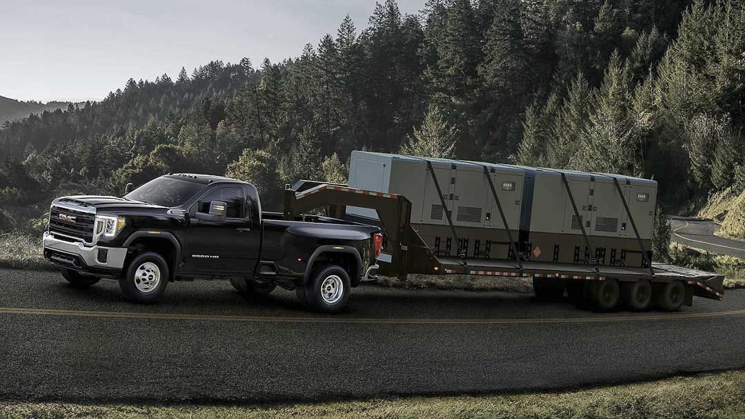 vue latérale du GMC Sierra Heavy Duty 2021 sur une route avec une remorque bien chargée