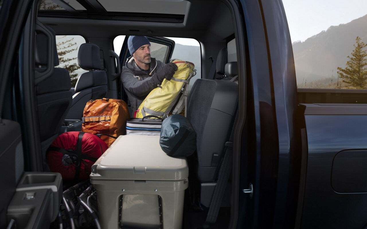 Vue intérieur arrière du Ford F-150 avec un homme débarquant l'équipement de camping